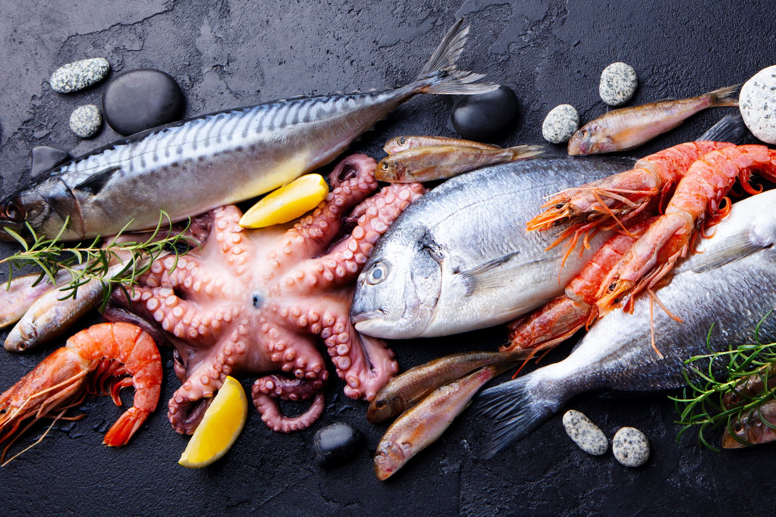 Fresh fish and seafood assortment on black slate background. Top view.