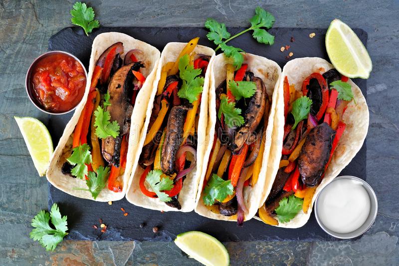 Can you tell me what diet is most effective at saving the planet and helping you live a longer life? portobello mushroom vegan fajitas above view dark slate background healthy eating plant based meat substitute concept 156204900